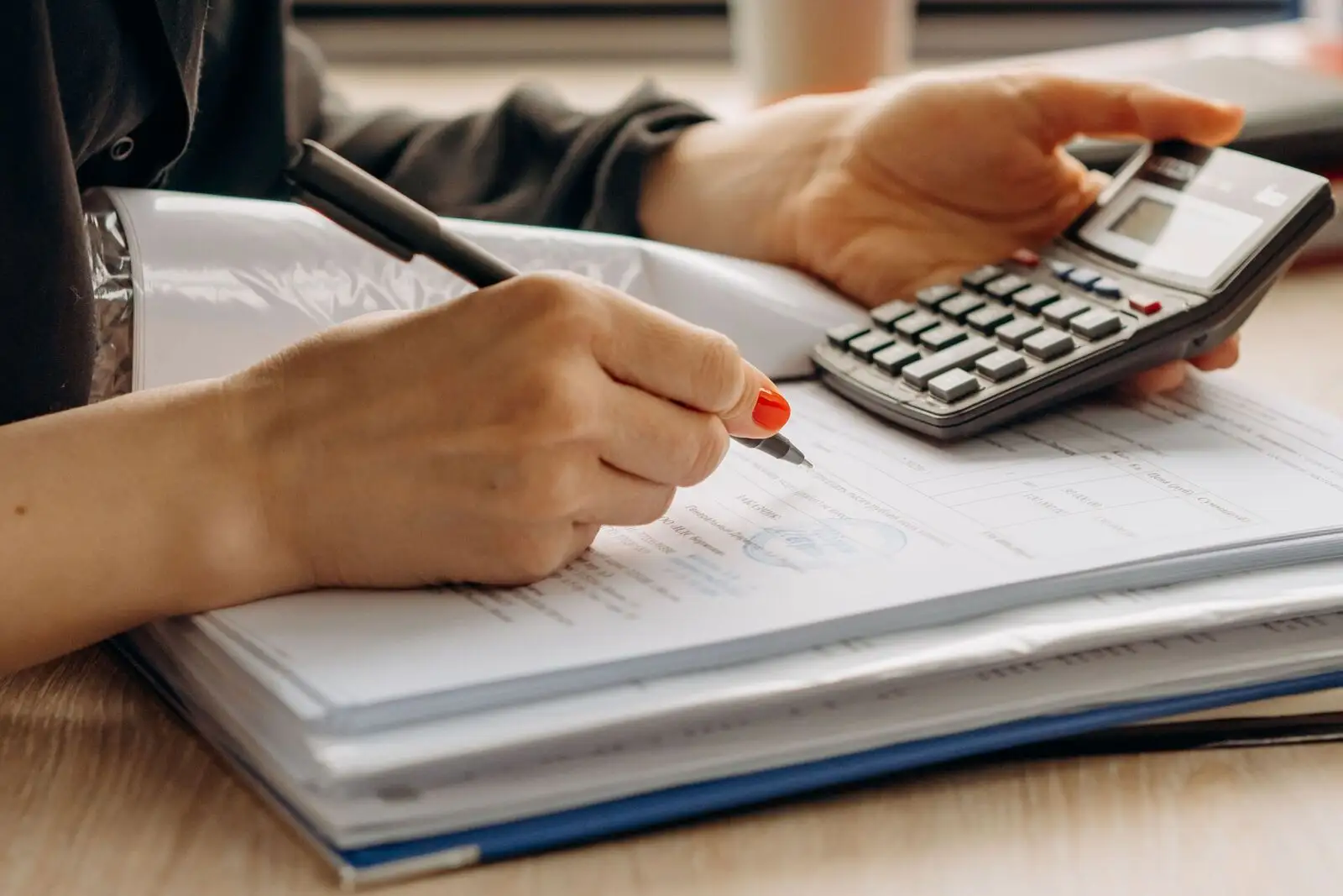 Personne vérifiant un document officiel avant de le signer, calculatrice à la main